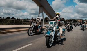 Motorradfahrer in stilvollen Harley-Davidson Maschinen fahren auf einer modernen Straße unter einem bewölkten Himmel.