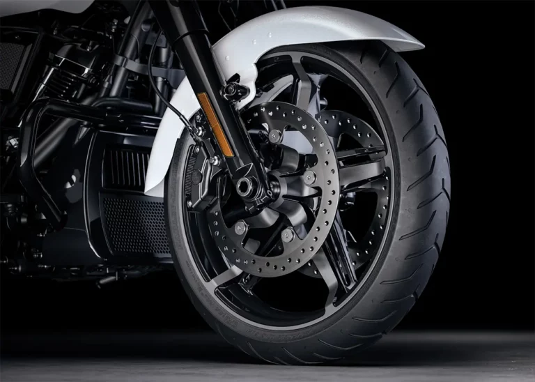 Nahaufnahme des vorderen Rades einer Harley-Davidson mit schwarzer Felge, breitem Reifen und modernen Bremsscheiben.