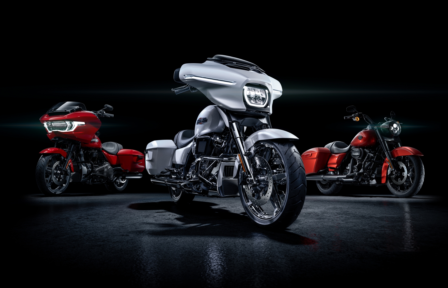 Drei beeindruckende Harley-Davidson Motorräder in Rot und Silber vor schwarzem Hintergrund, perfekt für Motorradliebhaber und -käufer.