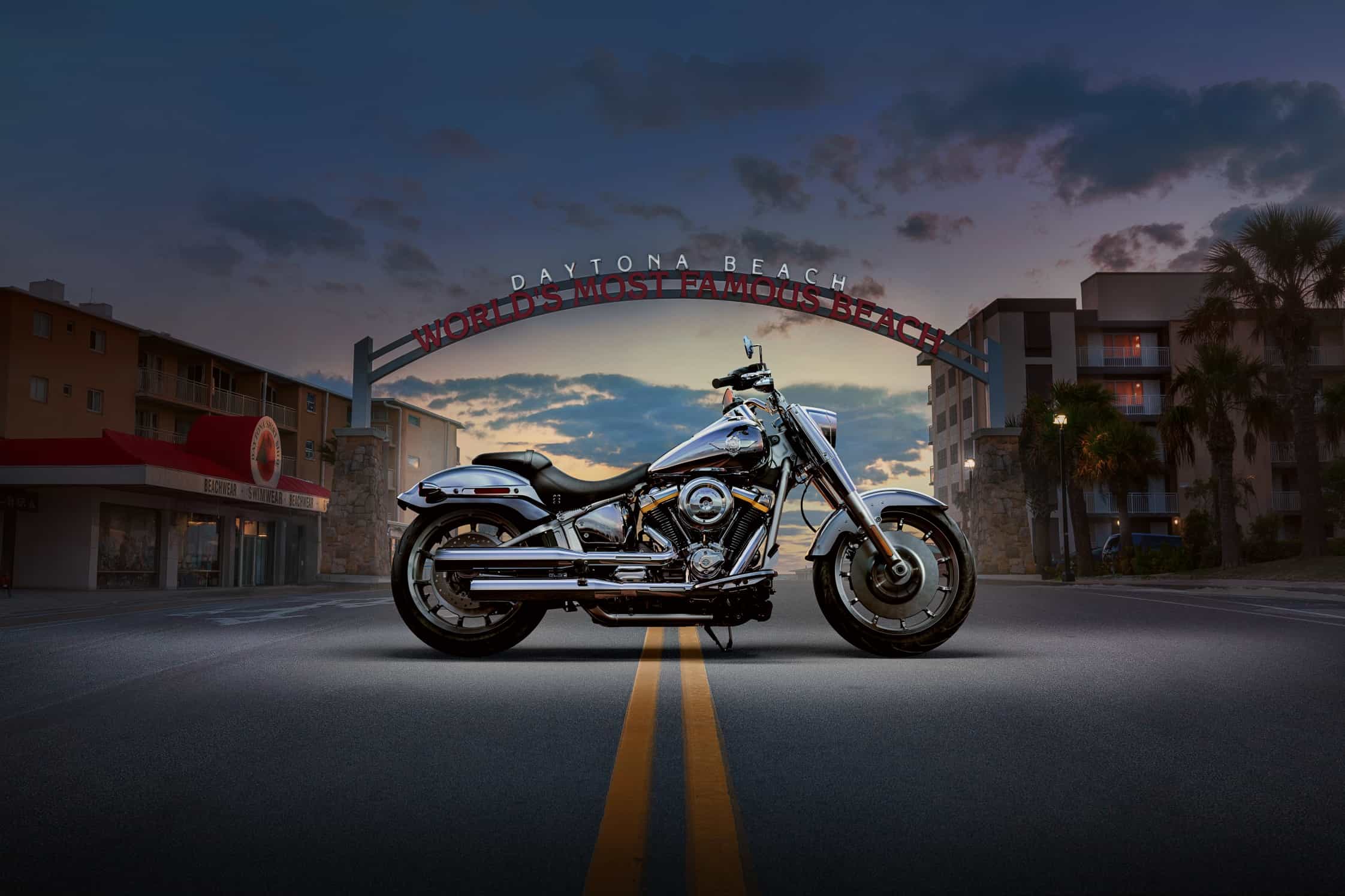 Eine glänzende Harley-Davidson-Motorrad steht auf einer Straße vor dem berühmten Daytona Beach-Schild bei Sonnenuntergang.