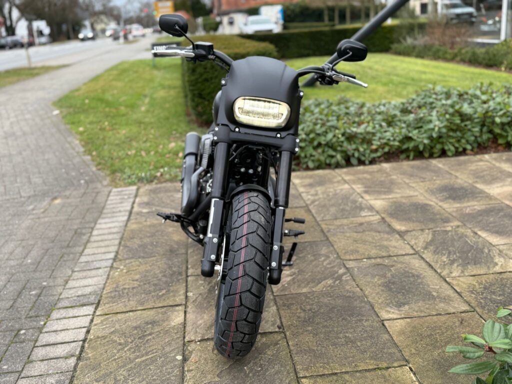 Ein schwarzes Harley-Davidson-Motorrad steht auf einem gepflasterten Weg vor einer grünen Rasenfläche.