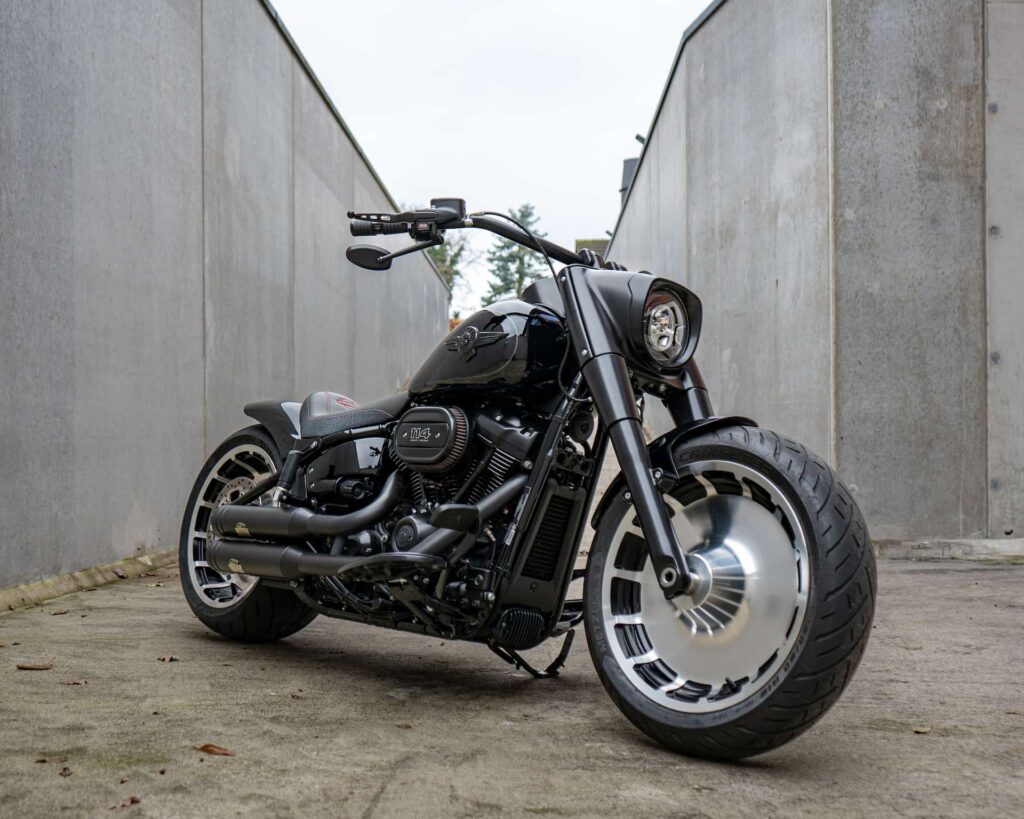 Ein schwarzes Harley-Davidson Motorrad steht in einer engen Gasse zwischen grauen Wänden und zeigt seine markante Bauweise und das leistungsstarke Design.