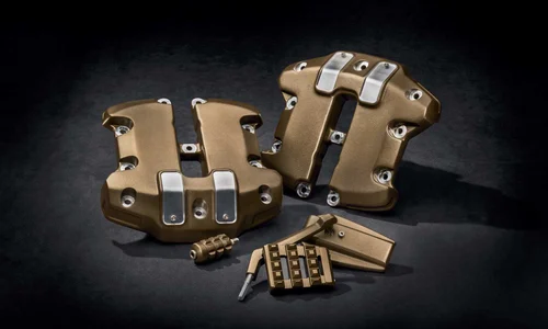 Zwei goldfarbene Motorradersatzteile mit verschiedenen Zubehörteilen für Harley-Davidson Motorräder auf schwarzem Hintergrund.