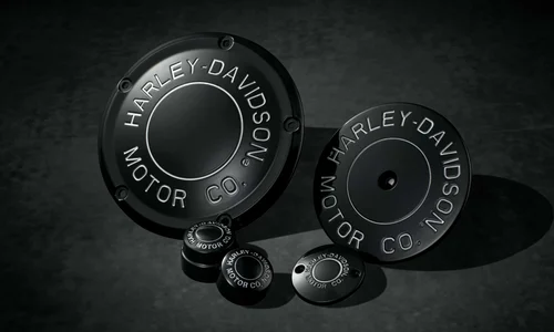 Verschiedene schwarze Harley-Davidson Motorabdeckungen und Zubehörteile auf einem dunklen Untergrund.