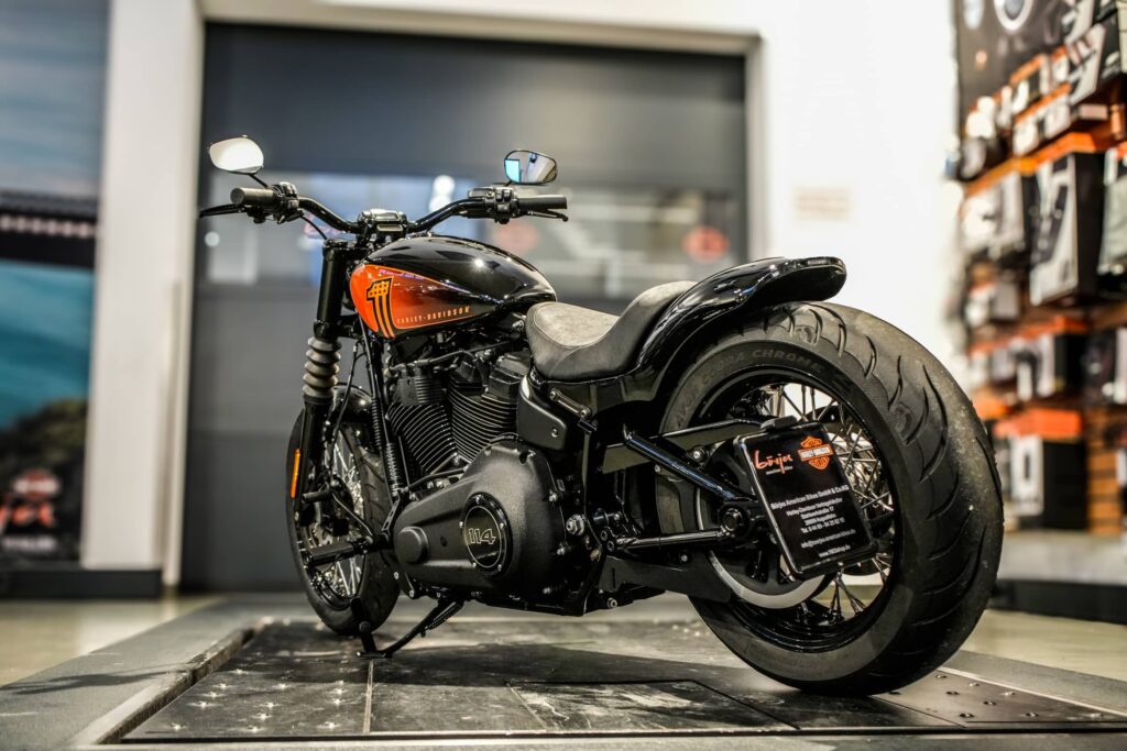 Ein stylisches Harley-Davidson Motorrad in schwarzer Lackierung mit orangefarbenen Akzenten steht auf einem Präsentationspodest im Showroom von Börjes American Bikes.