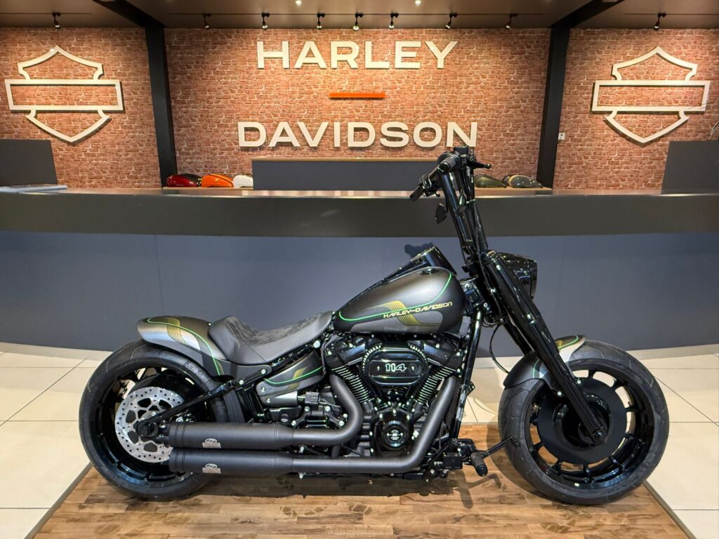 Ein modifiziertes Harley-Davidson-Motorrad in einem modernen Verkaufsraum mit Backsteinwand und Harley-Davidson-Logo im Hintergrund.