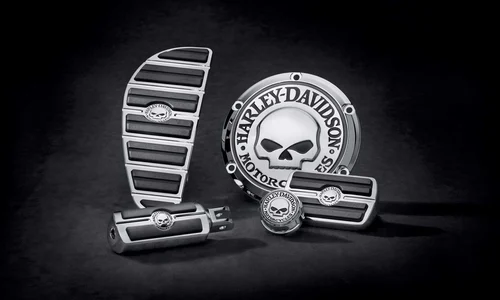 Verschiedene Harley-Davidson Motorradteile mit einem markanten Totenkopf-Design auf schwarzem Hintergrund.